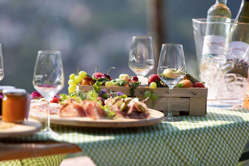 Csm landidyll weinhotel klostermuehle ockfen saar picknicktisch im weinberg bei sonnenschein mit saarwein obst und schinken rustikal gedeckter tisch mit karierter tischdecke 5bb602e46a
