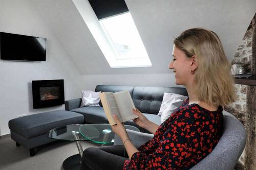 Csm piepers landidyll hotel bad laer behagliche zimmer und suiten blick auf kamin und fernseher lesende junge dame im sessel michaelmeyer foto