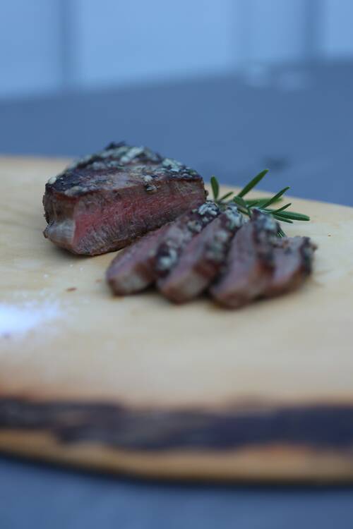 Thinly sliced eye fillet steak with homemade garlic & herb butter. Garnished with fresh Rosmary.